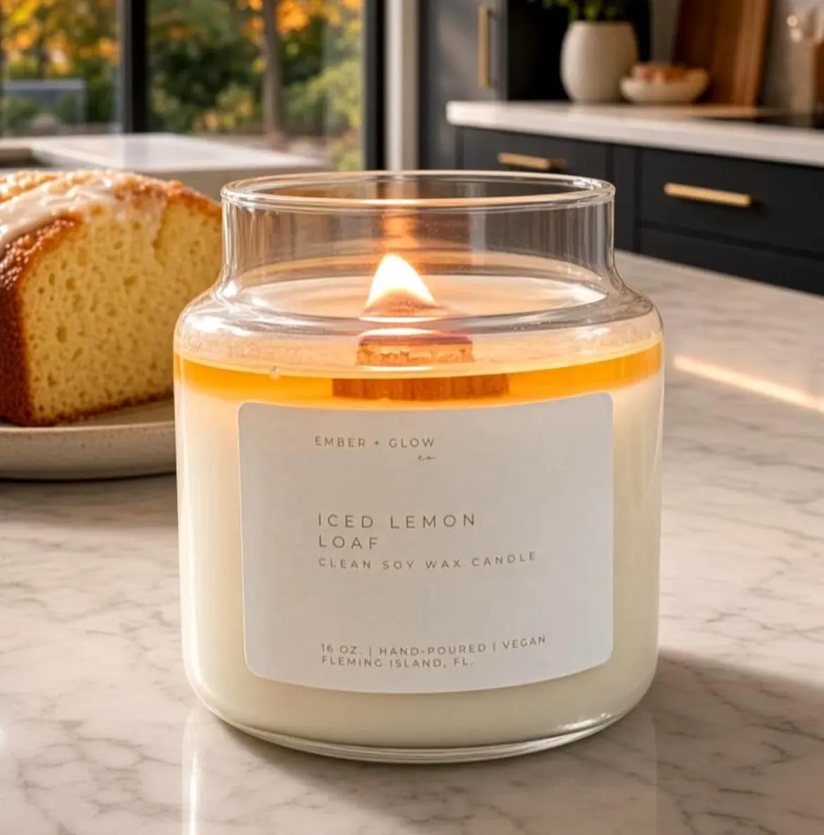 Lit Iced Lemon Loaf soy candle with a wood wick on a marble kitchen counter